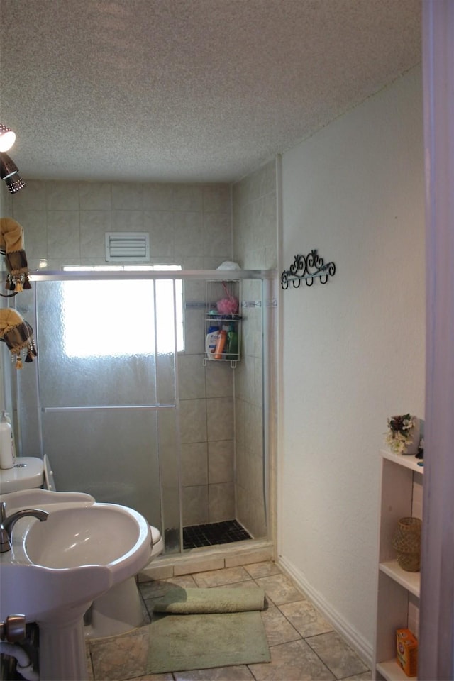 bathroom featuring a textured ceiling, visible vents, and a shower stall