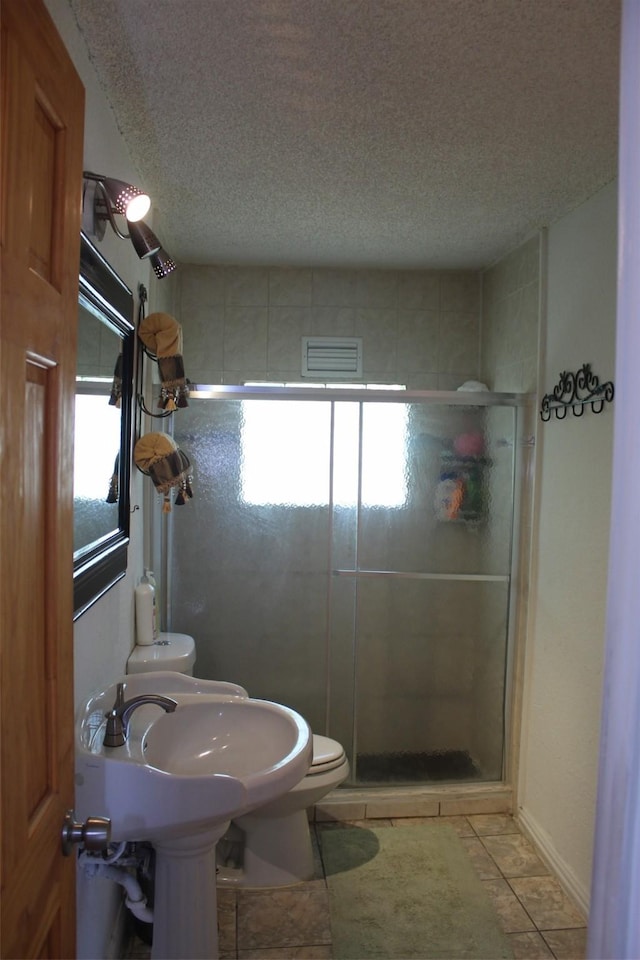 full bathroom with a shower stall, toilet, a textured ceiling, and visible vents