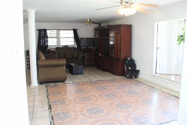 living area featuring a ceiling fan, decorative columns, and light tile patterned flooring
