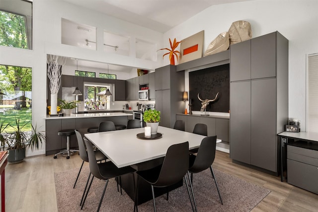 dining space featuring light wood-style flooring and high vaulted ceiling