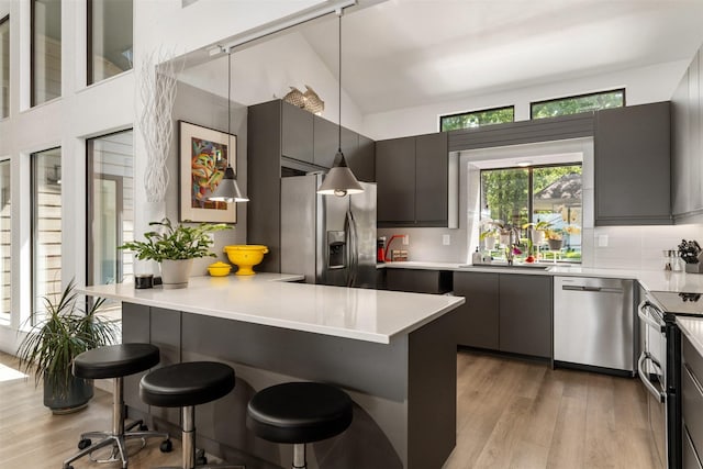 kitchen featuring light wood finished floors, stainless steel appliances, light countertops, and a breakfast bar area