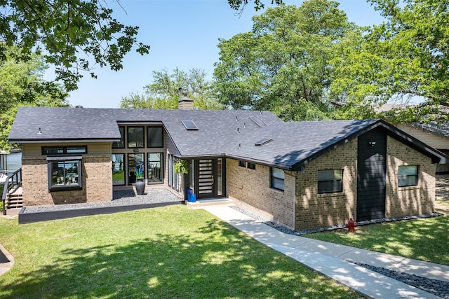 view of front of property with a chimney, a front lawn, brick siding, and a shingled roof