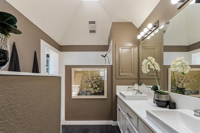 bathroom with vaulted ceiling, visible vents, a sink, and a walk in shower