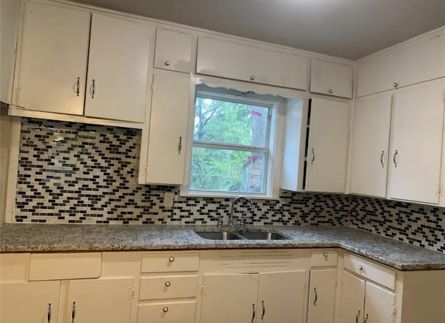 kitchen featuring a sink, tasteful backsplash, and white cabinets
