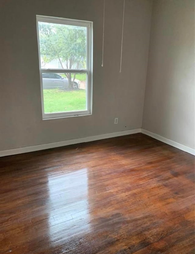 spare room with dark wood-type flooring and baseboards