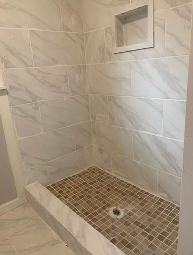 full bath featuring tiled shower and marble finish floor