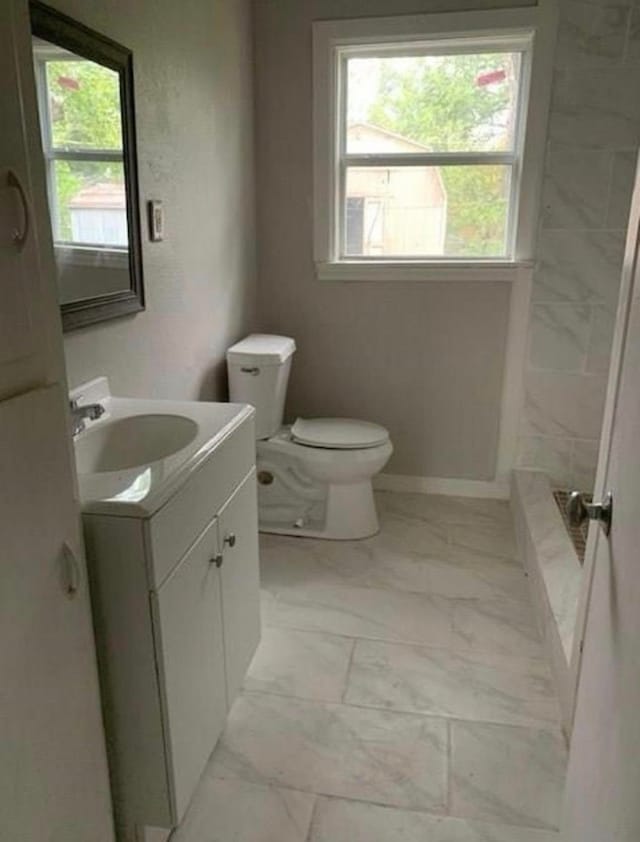 bathroom with toilet, marble finish floor, plenty of natural light, and vanity