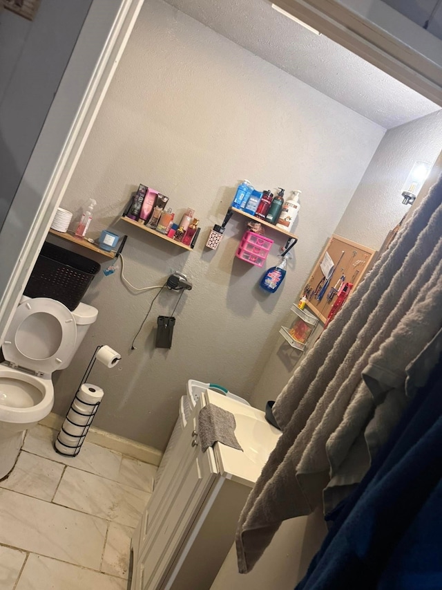 bathroom with tile patterned floors, baseboards, and toilet