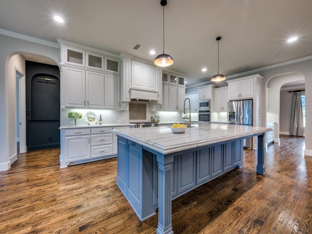 kitchen with arched walkways, recessed lighting, white cabinetry, and stainless steel appliances