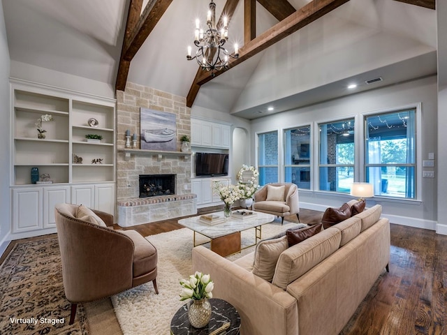 living area with an inviting chandelier, dark wood-type flooring, beam ceiling, and a stone fireplace