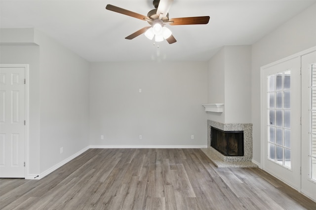 unfurnished living room with a fireplace, wood finished floors, ceiling fan, and baseboards