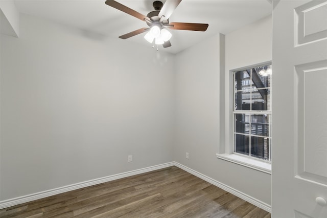 spare room featuring dark wood-style floors, ceiling fan, and baseboards
