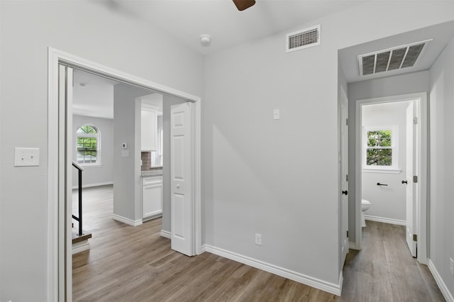hall with visible vents, wood finished floors, and baseboards