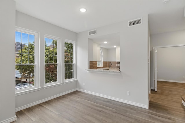 unfurnished living room with visible vents, wood finished floors, and baseboards