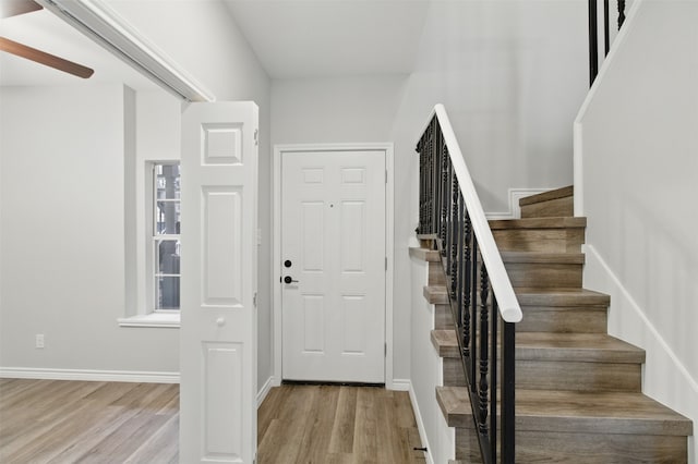 foyer featuring baseboards, light wood-type flooring, and stairway