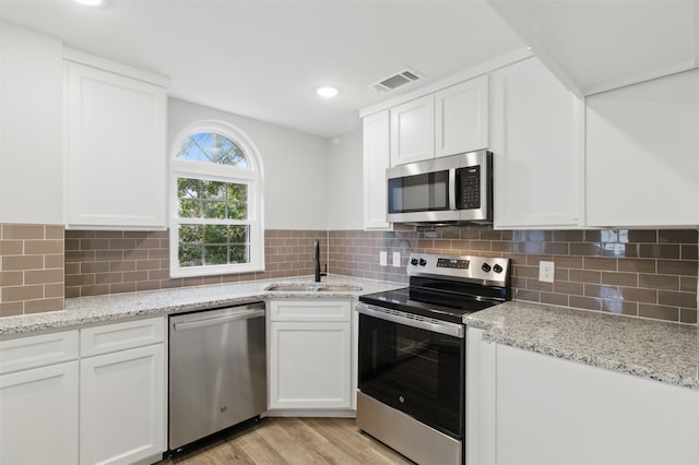 kitchen featuring a sink, light wood-type flooring, visible vents, white cabinets, and appliances with stainless steel finishes