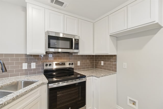 kitchen featuring a sink, stainless steel appliances, tasteful backsplash, visible vents, and white cabinetry