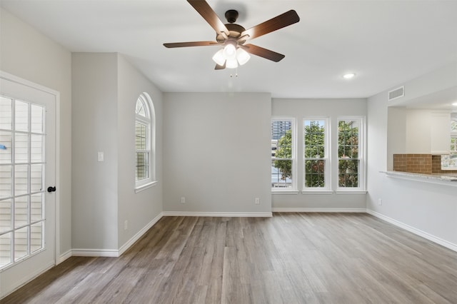 unfurnished living room featuring wood finished floors, visible vents, ceiling fan, and baseboards