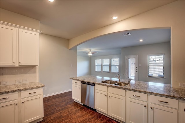kitchen with dishwasher, a sink, arched walkways, light stone countertops, and ceiling fan