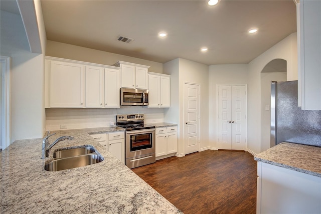 kitchen with a sink, decorative backsplash, stainless steel appliances, white cabinetry, and dark wood-style flooring