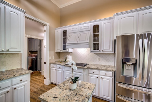 kitchen with stainless steel fridge with ice dispenser, ornamental molding, glass insert cabinets, white cabinetry, and backsplash