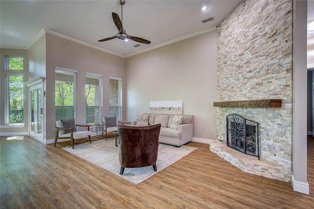 living area featuring visible vents, a ceiling fan, crown molding, and wood finished floors