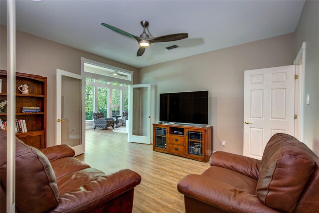 living area featuring visible vents, light wood-type flooring, and a ceiling fan