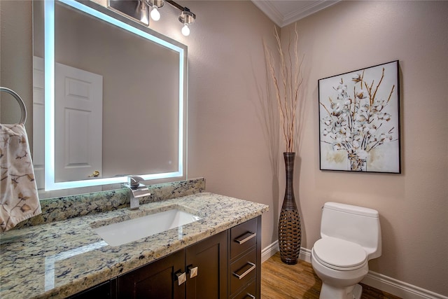 bathroom featuring vanity, ornamental molding, toilet, wood finished floors, and baseboards
