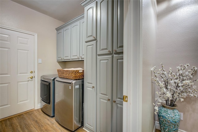 laundry area with light wood finished floors, washing machine and dryer, and cabinet space