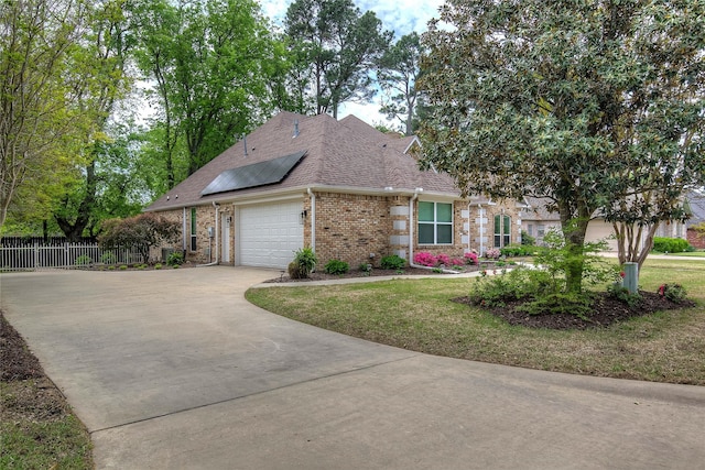 view of side of home with roof mounted solar panels, brick siding, an attached garage, a shingled roof, and driveway