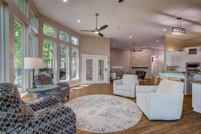 living area with ornamental molding, ceiling fan, a fireplace, recessed lighting, and dark wood-type flooring