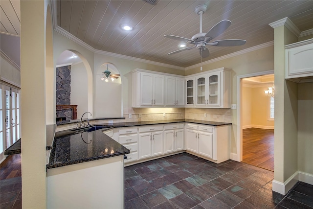 kitchen featuring dark stone counters, ceiling fan, a sink, and plenty of natural light