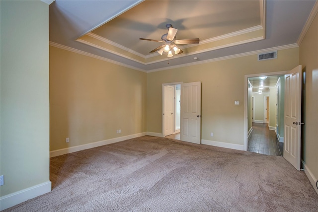 unfurnished bedroom with ornamental molding, carpet flooring, a tray ceiling, and visible vents