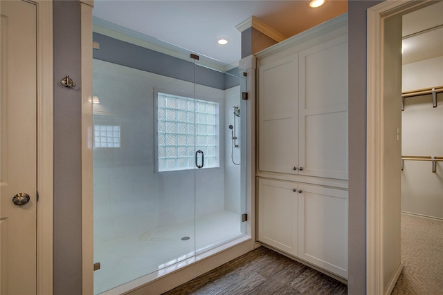 full bath featuring recessed lighting, a shower stall, a spacious closet, and wood finished floors