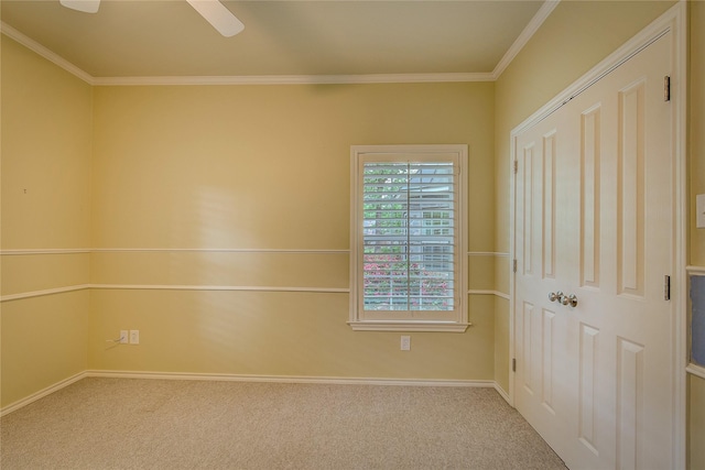 spare room featuring ceiling fan, carpet floors, baseboards, and ornamental molding