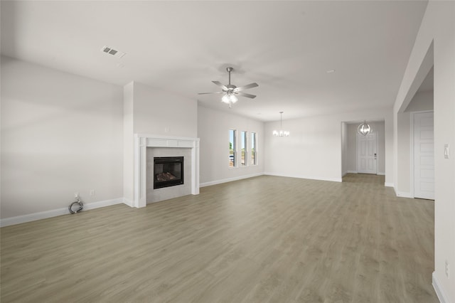 2413 Rams Horn, Waxahachie, TX 75167 - unfurnished living room with a tiled fireplace, light wood-type flooring, ceiling fan with notable chandelier, baseboards, and visible vents