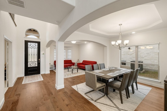 14662 Gentle Breeze Rd, Frisco, TX 75035 - dining area featuring a notable chandelier, visible vents, a raised ceiling, arched walkways, and wood finished floors