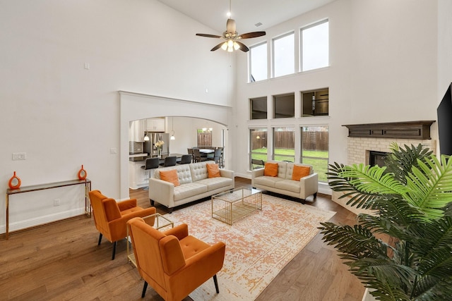 14662 Gentle Breeze Rd, Frisco, TX 75035 - living area with a brick fireplace, arched walkways, a high ceiling, and hardwood / wood-style flooring