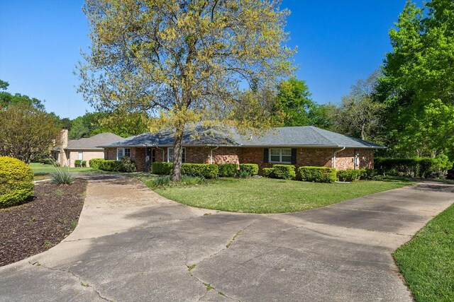 single story home featuring a front yard, brick siding, and concrete driveway