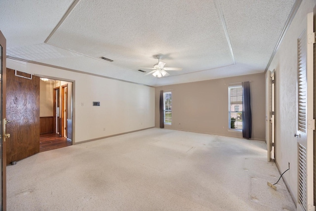 spare room with crown molding, a textured ceiling, a ceiling fan, visible vents, and carpet flooring