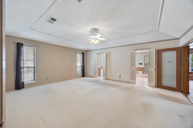 carpeted spare room featuring a textured ceiling, a healthy amount of sunlight, and a ceiling fan
