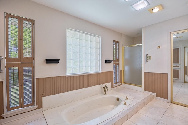 full bath with a bath, tile patterned flooring, wainscoting, a stall shower, and wooden walls
