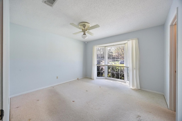 spare room with carpet flooring, baseboards, a ceiling fan, and visible vents