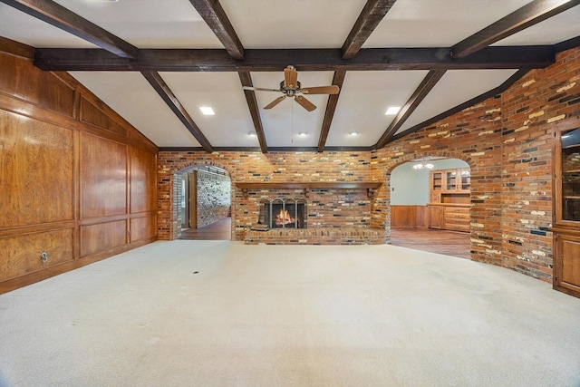 unfurnished living room with arched walkways, carpet, a fireplace, and ceiling fan