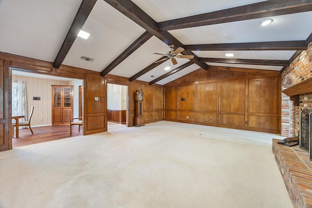unfurnished living room with visible vents, a brick fireplace, ceiling fan, carpet, and vaulted ceiling with beams