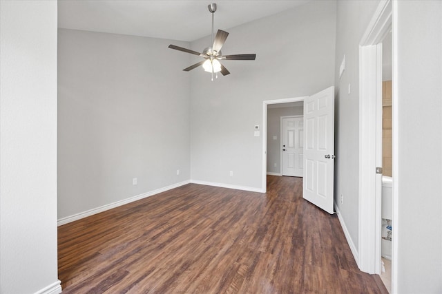 empty room featuring ceiling fan, dark wood-type flooring, baseboards, and vaulted ceiling