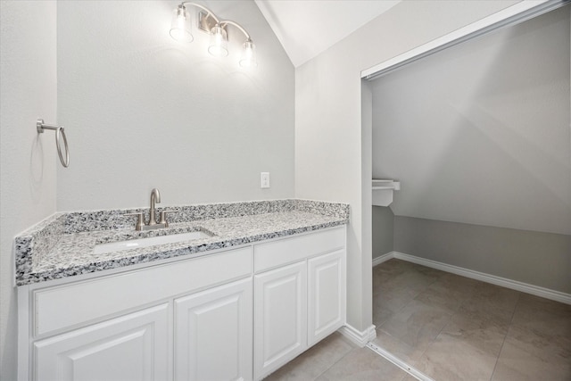 bathroom featuring lofted ceiling, baseboards, vanity, and tile patterned flooring