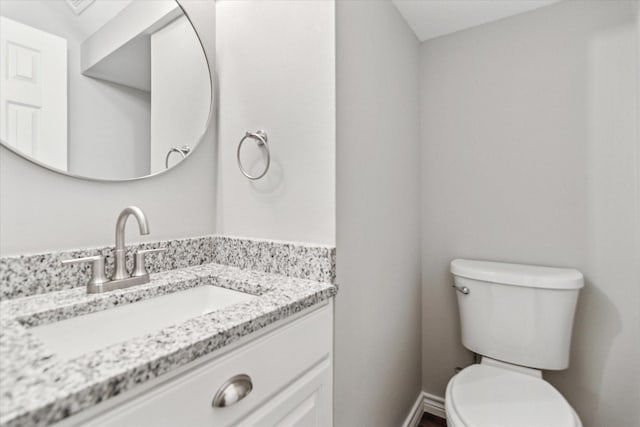 half bath with toilet, vanity, and baseboards