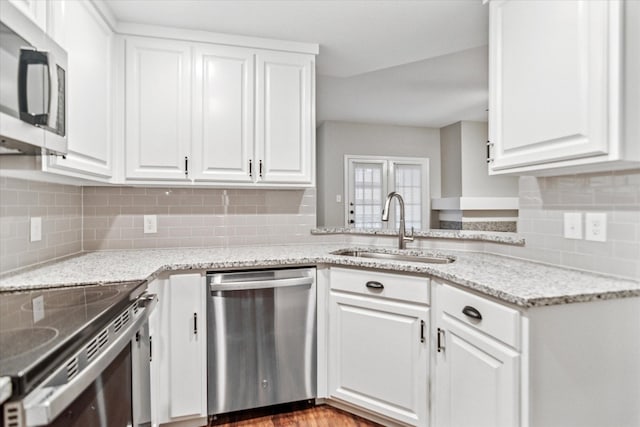 kitchen featuring dishwasher, a sink, white cabinets, and tasteful backsplash