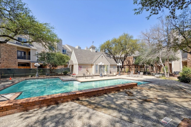 community pool featuring a patio area, fence, and a residential view